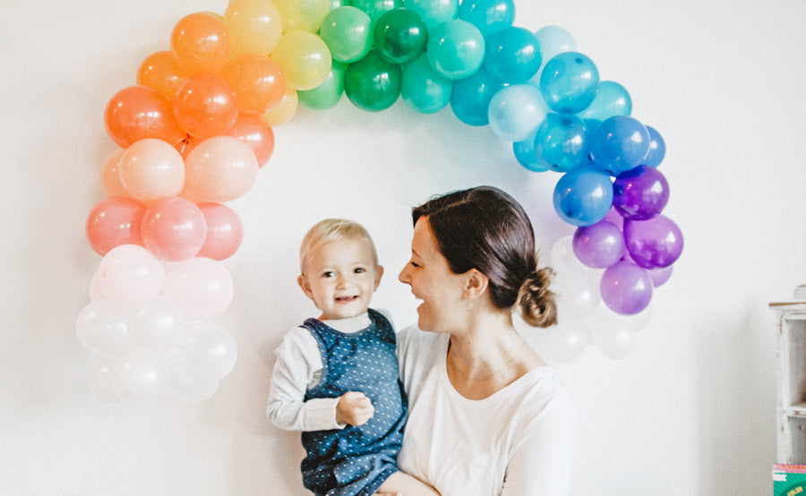Mom and Daughter standing in front of a rainbow balloon photo backdrop