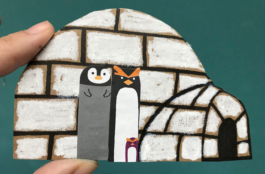 Completed DIY paper ornament of an igloo and penguin family