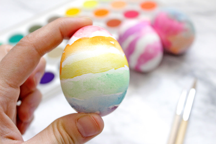 Holding a decorated Easter egg colored with watercolor paints