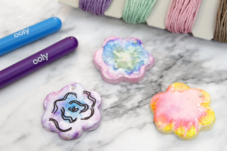 Three colored DIY clay pendants and OOLY Chroma Blends watercolor brush markers