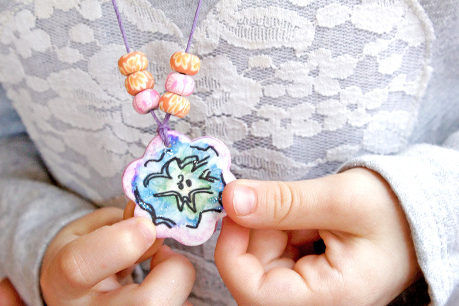 Child holding DIY clay necklace