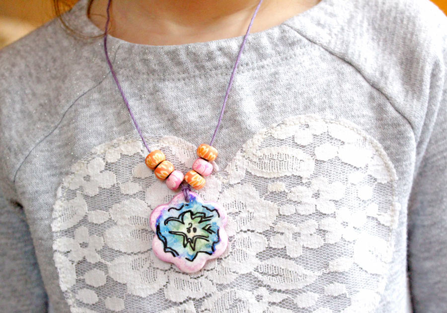 Girl wearing finished DIY clay pendant with beads