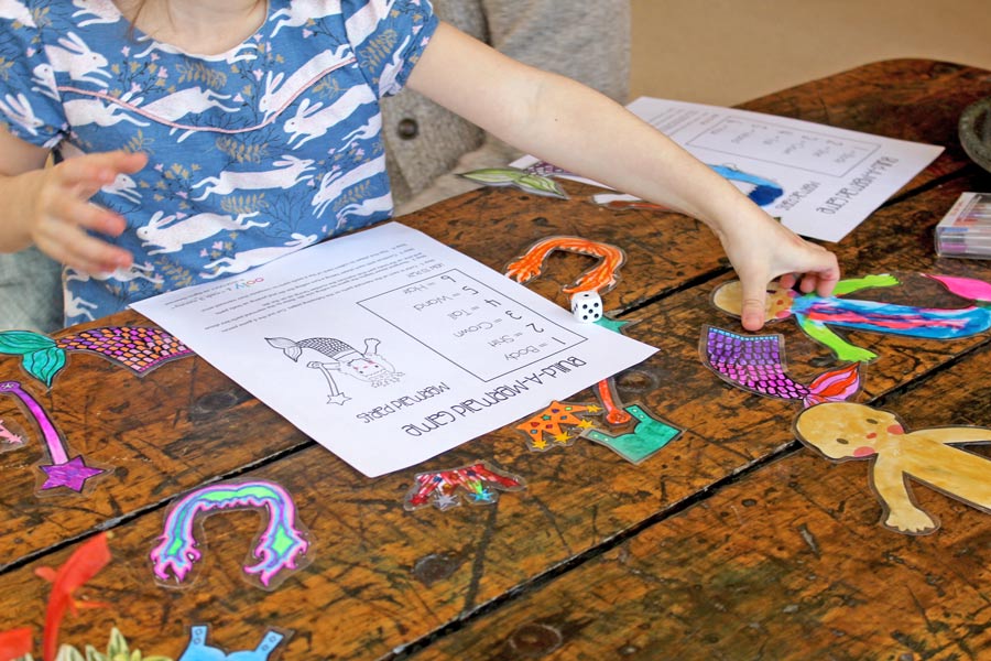 Girl piecing together colored mermaid from printable coloring game