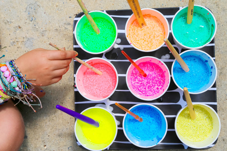 Girl mixing colored sidewalk chalk paint in paper cups