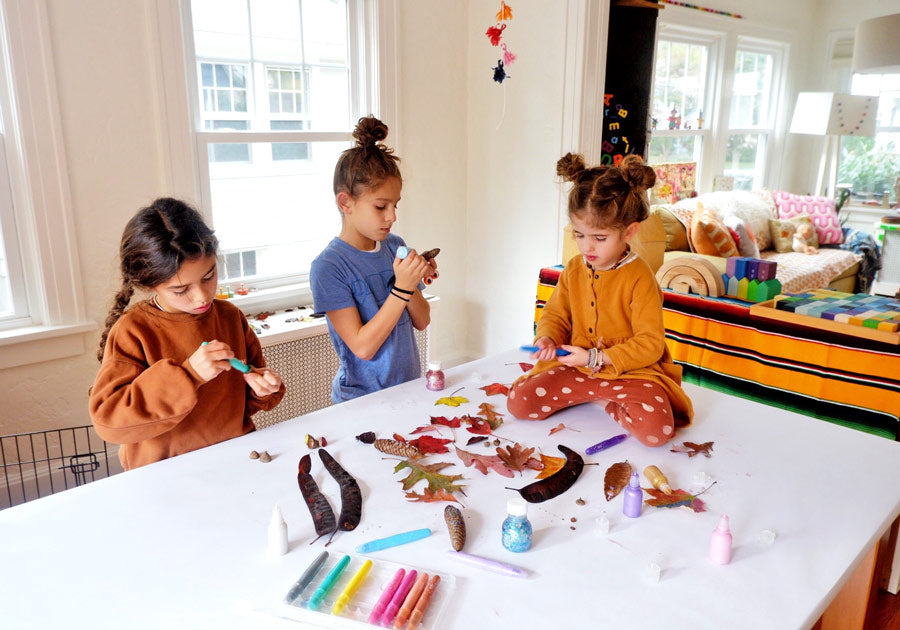 Girls gathered around a table doing fall crafting with autumn leaves