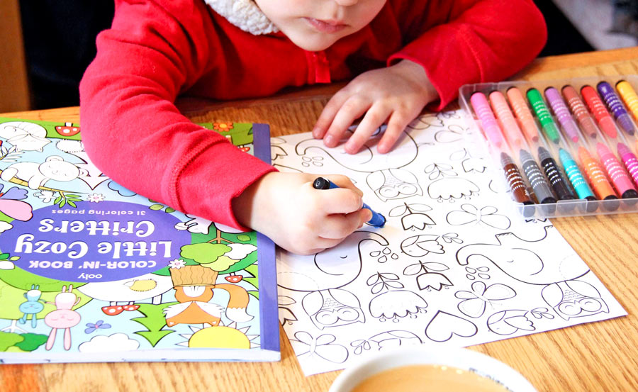 Girl coloring in Little Cozy Critters with OOLY markers