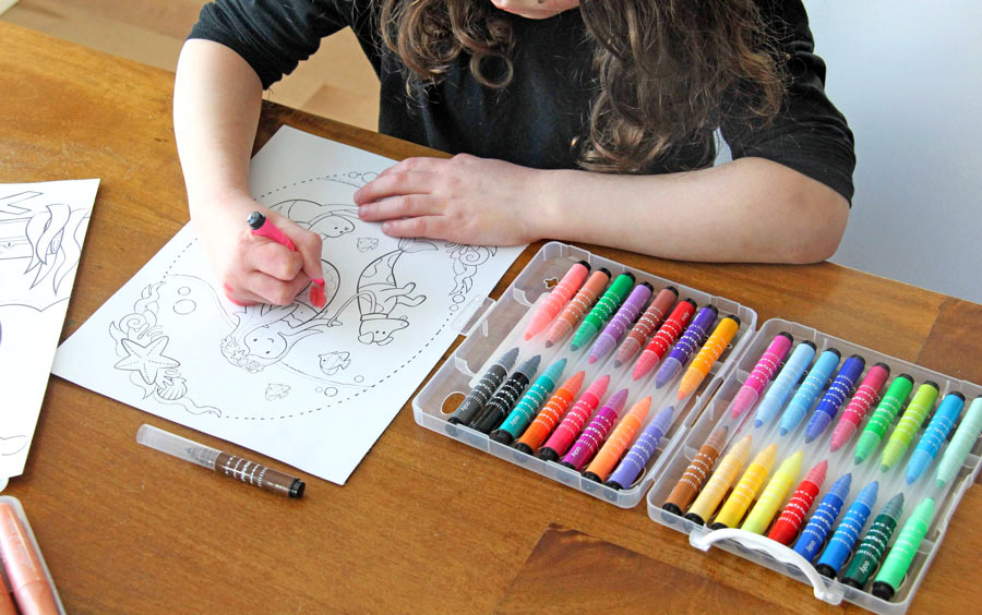 Girl coloring in coloring book with OOLY markers