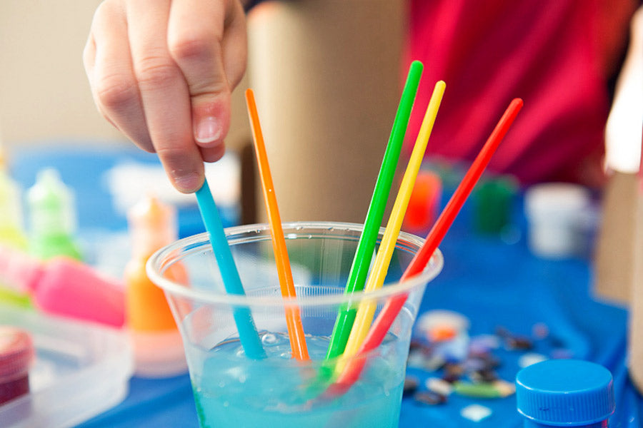 Kid holding colorful paintbrushes in water