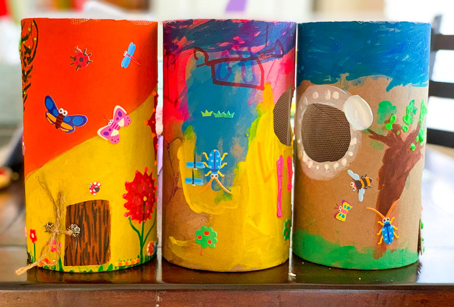 3 completed DIY bug hotels made with paper tubing and decorated with stickers, paint etc.