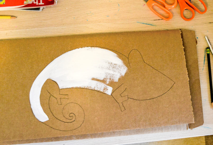 Outline of chameleon craft with white paint on cardboard