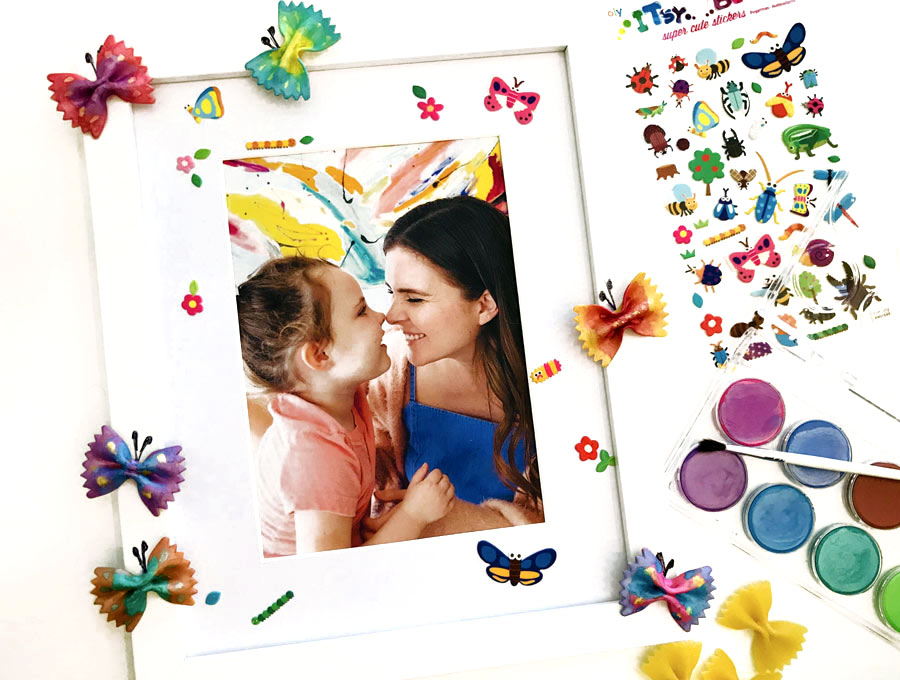 white framed photo of mother and child with colorfully painted noodles on edge of frame