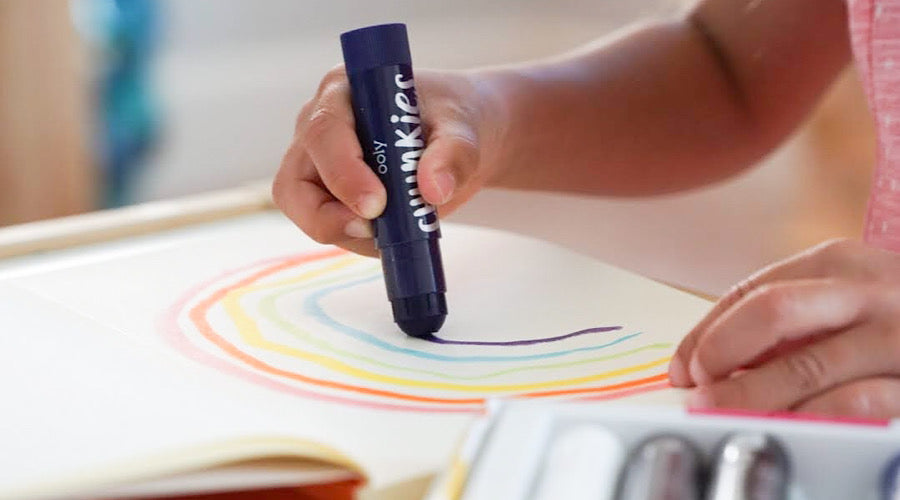 child hand holding chunkies paint stick coloring rainbow