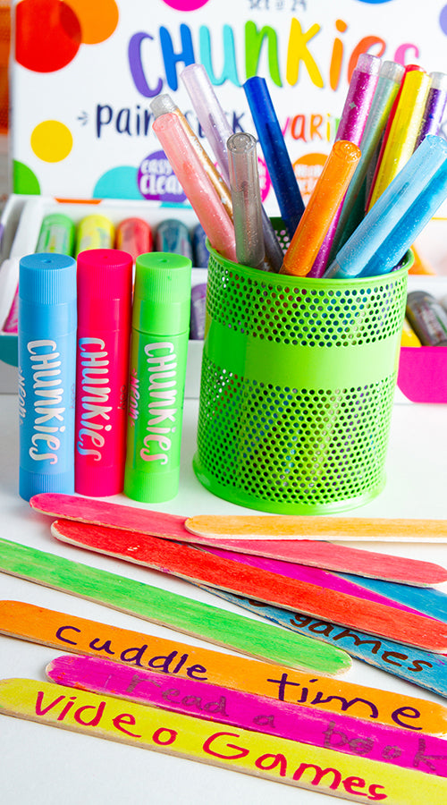 green pencil holder with colorful pens and chunkies paint sticks behind colorful popsicle sticks