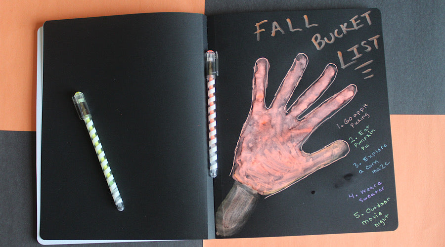 fall bucket list written on black paper with hand print on orange and black background