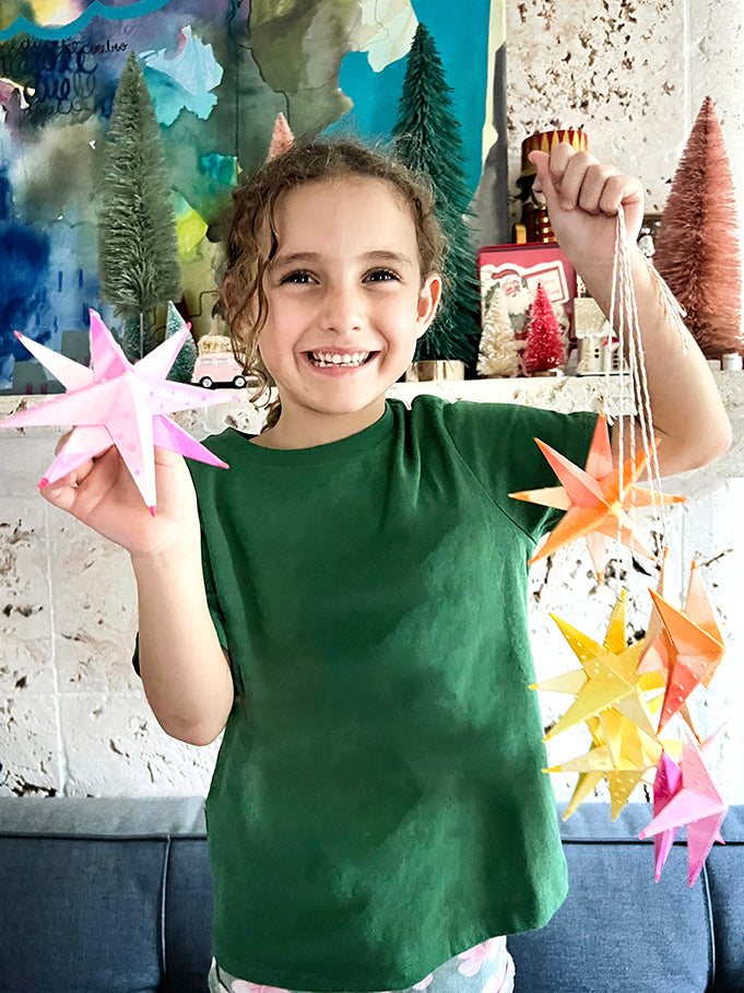 Child holding colorful stars in front of Holiday backdrop