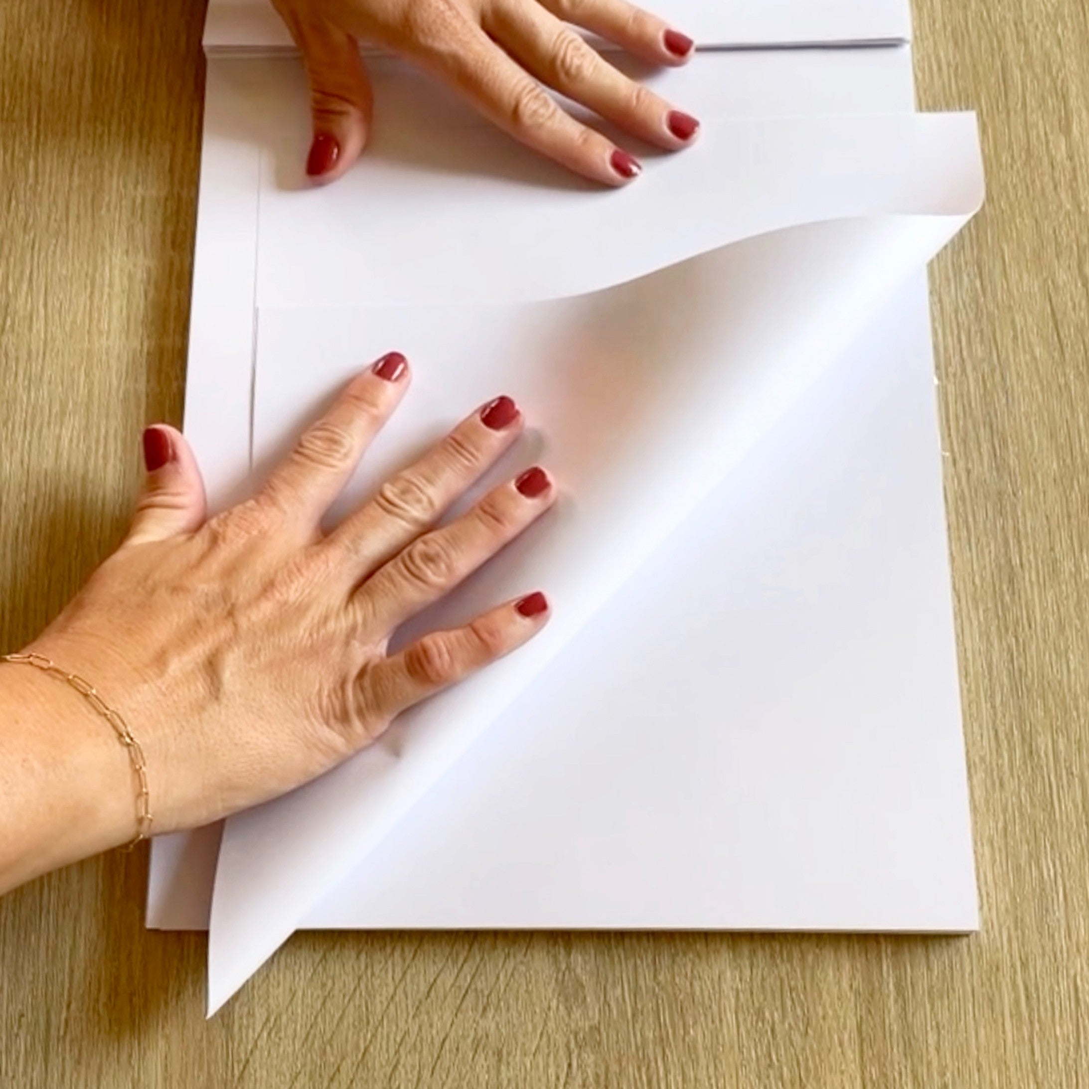 Two hands folding white paper on a table