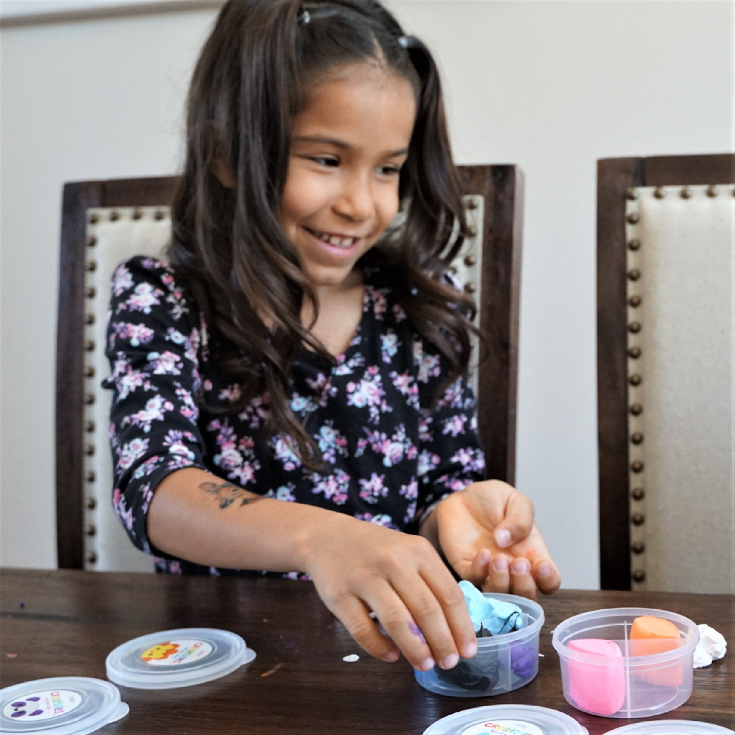 Girl standing at table playing with colorful clay