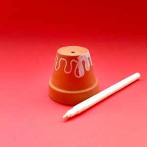 Plant holder upside down on a table with white marker and squiggles on a red background