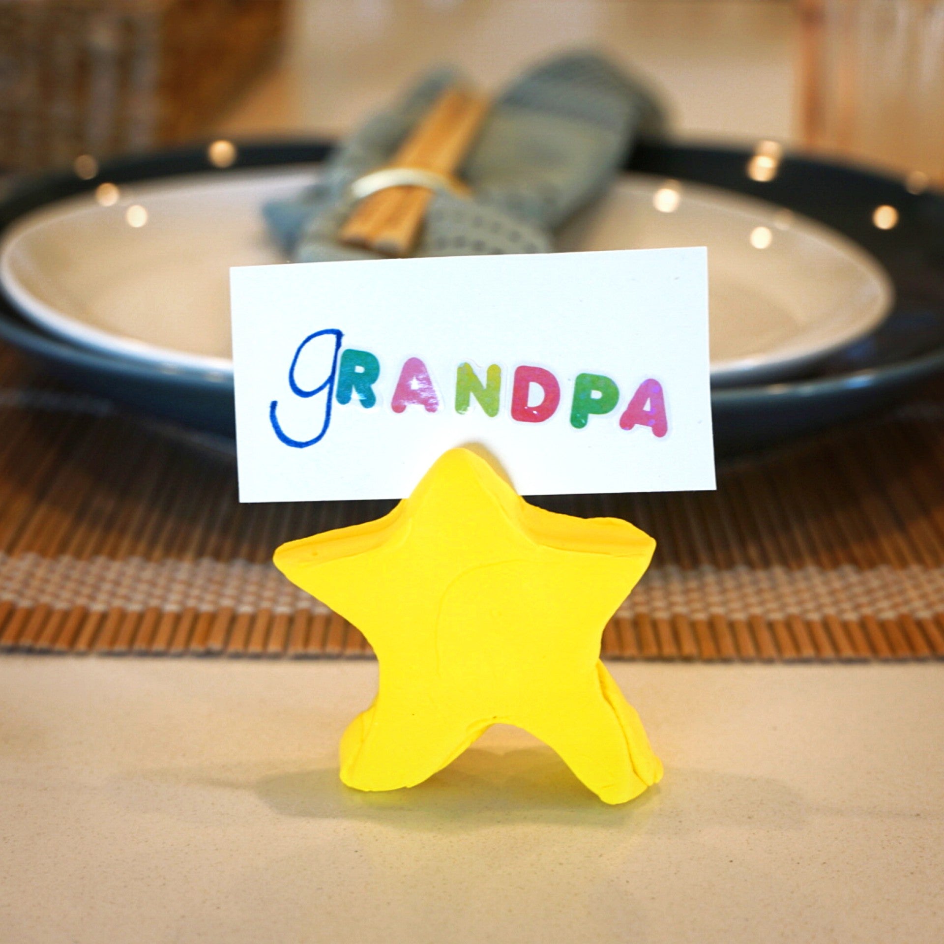 Yellow clay star holding grandpa name card in front of holiday place settings on a table