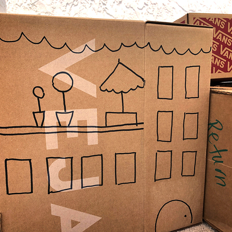 Cardboard box with windows and doors drawn on it