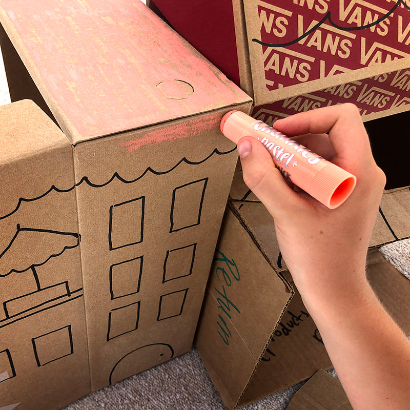 Hand holding chunkies paint stick painting a cardboard box building