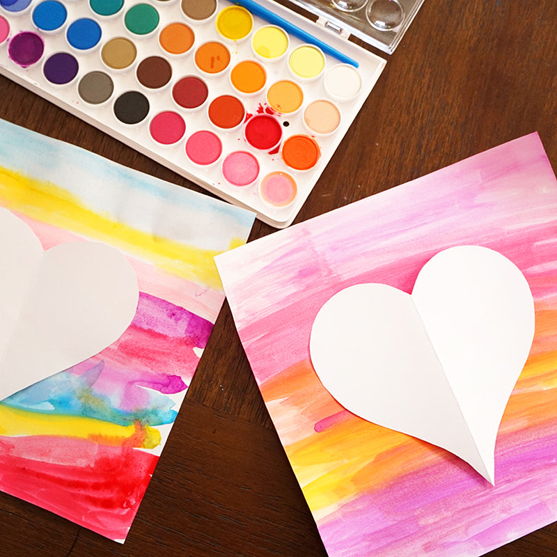 Cut out hearts on top of colorful valentine's day cards near paint set