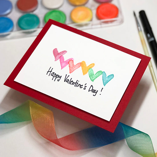 Valentine's Day card with colorful hearts and paints and ribbons on the table