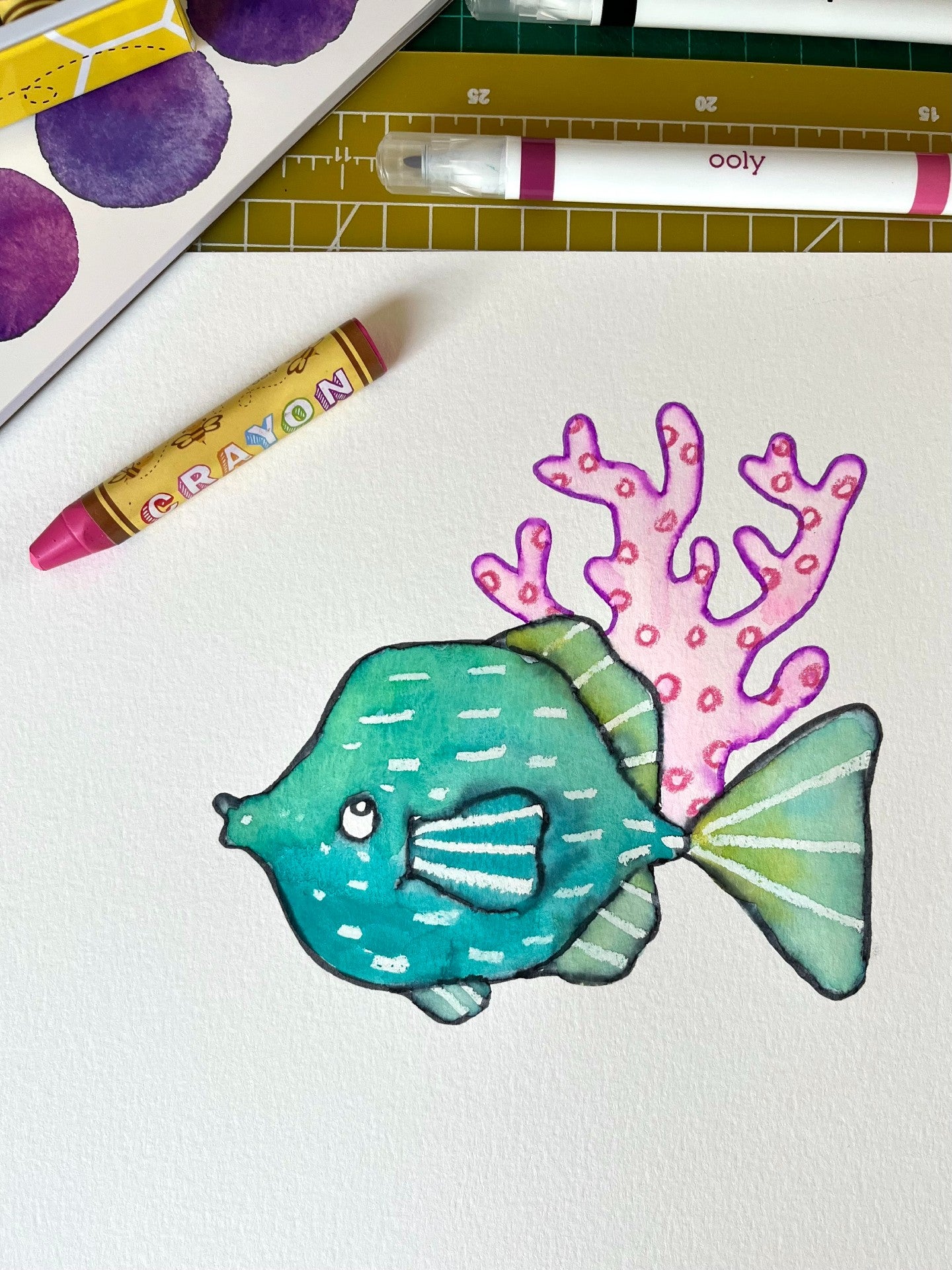 Colorful fish with purple coral on paper with a crayon and marker