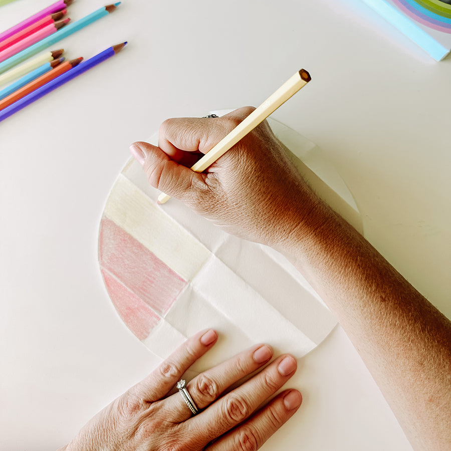 Person using colored pencils to color in different grids on circular paper