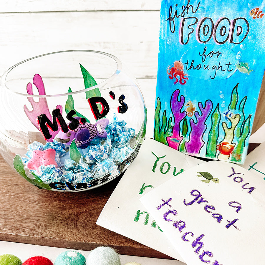 Colorful handmade fish bowl with greeting cards on a wooden plank