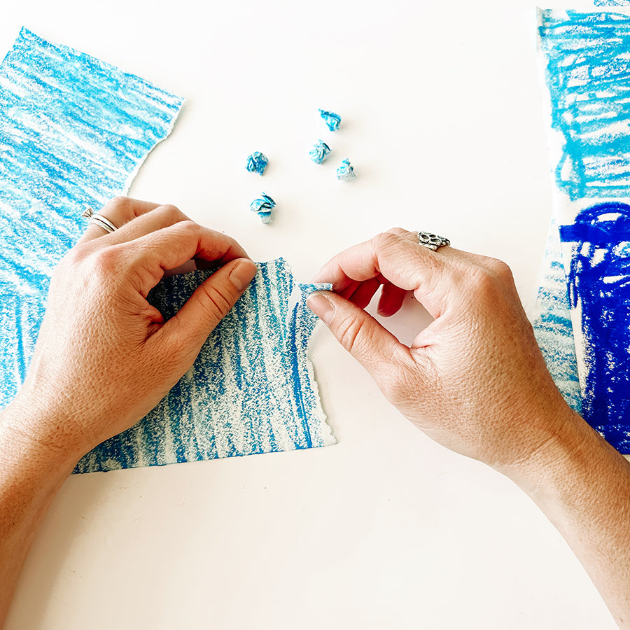 Adult hands ripping up blue paper and crumbling them into balls
