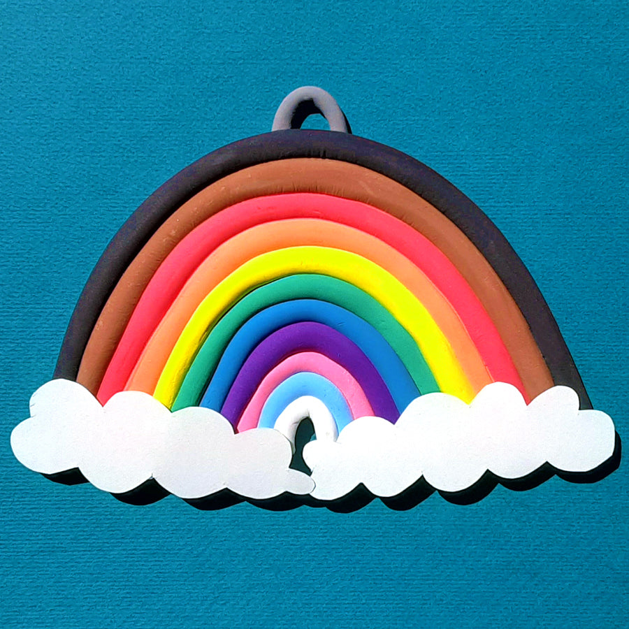 Finished clay rainbow with 11 rolled out dry clay pieces in every color and white cloud paper attached to the bottom