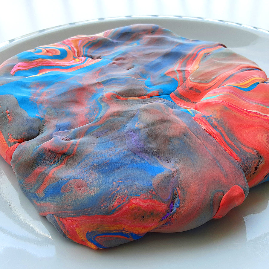 Close up of colorful clay mixed up in a thick slab sitting on a white plate