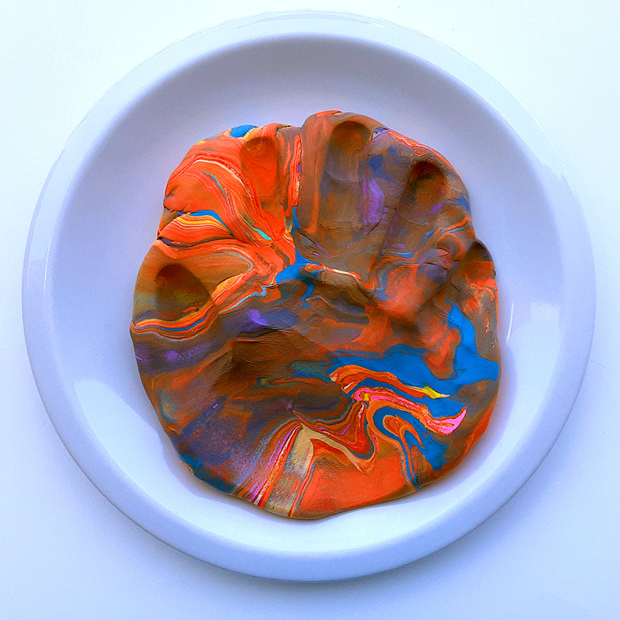 Overhead image of hand imprint on colorful clay slap sitting on white plate