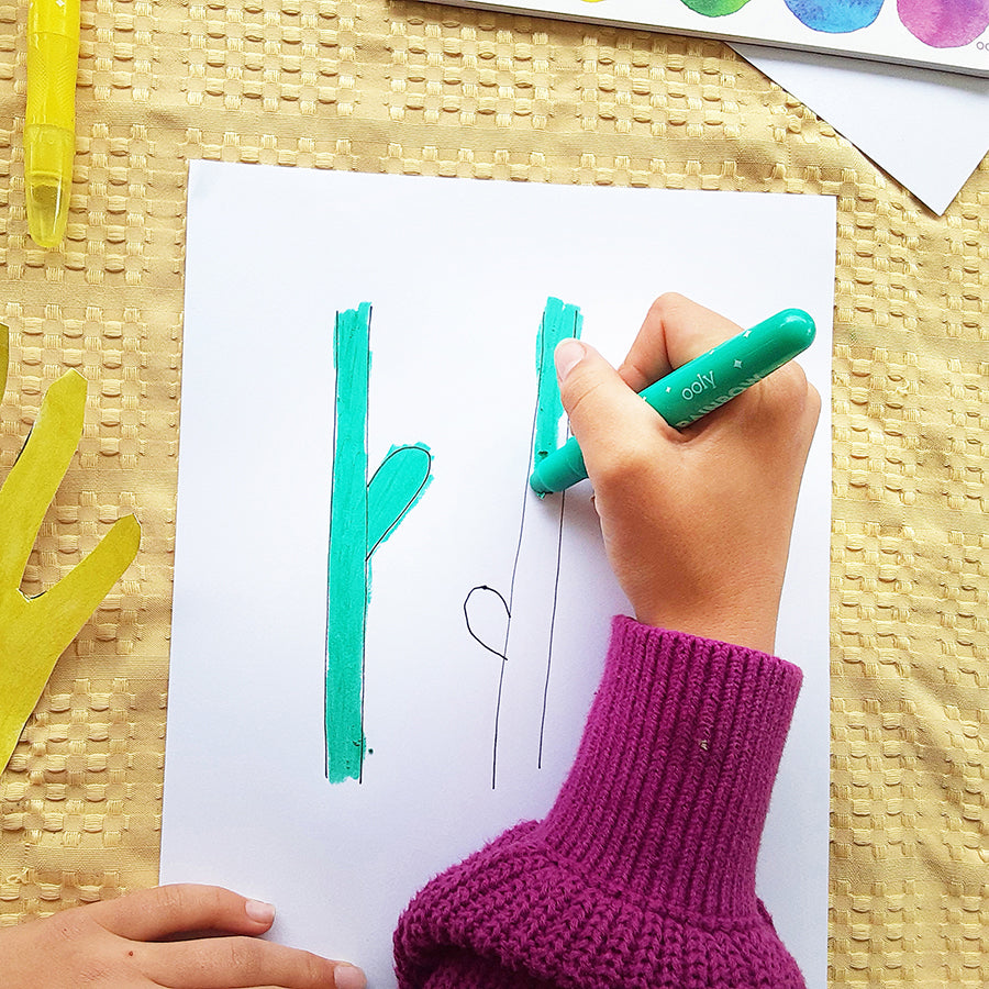 Kid using Rainbow Sparkle Gel Crayons to color in green stems for flower craft