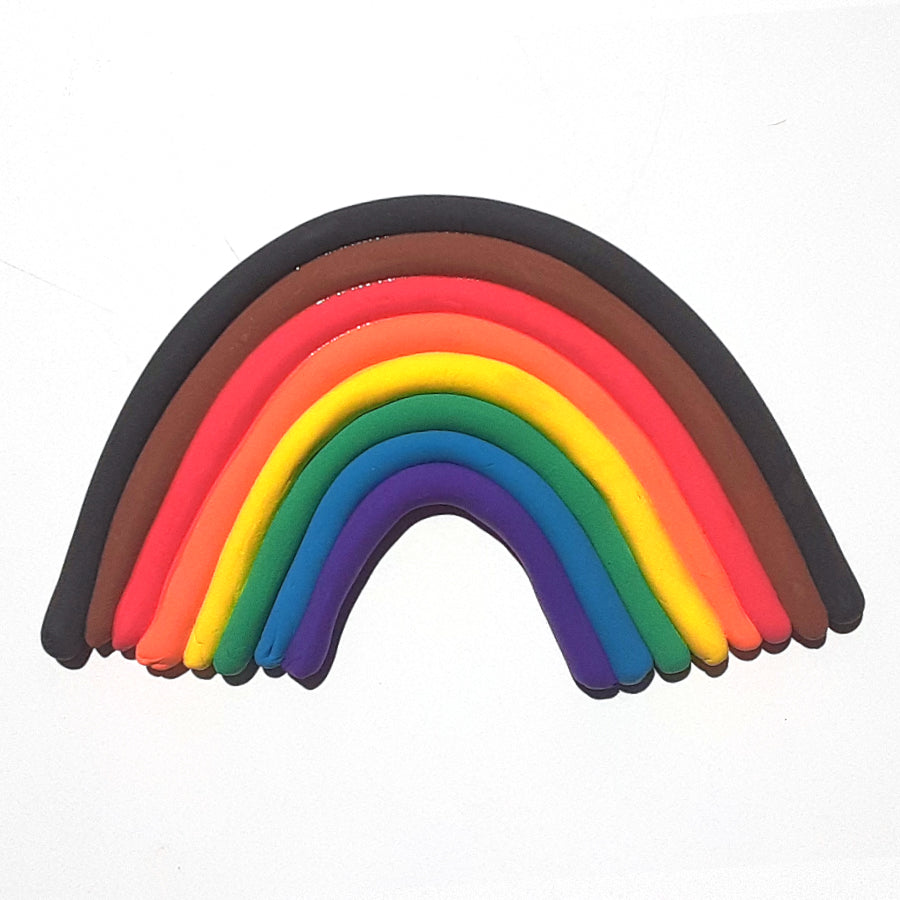 Purple, blue, green, yellow, orange, red, brown, and black dry clay rolled out into the shape of a rainbow