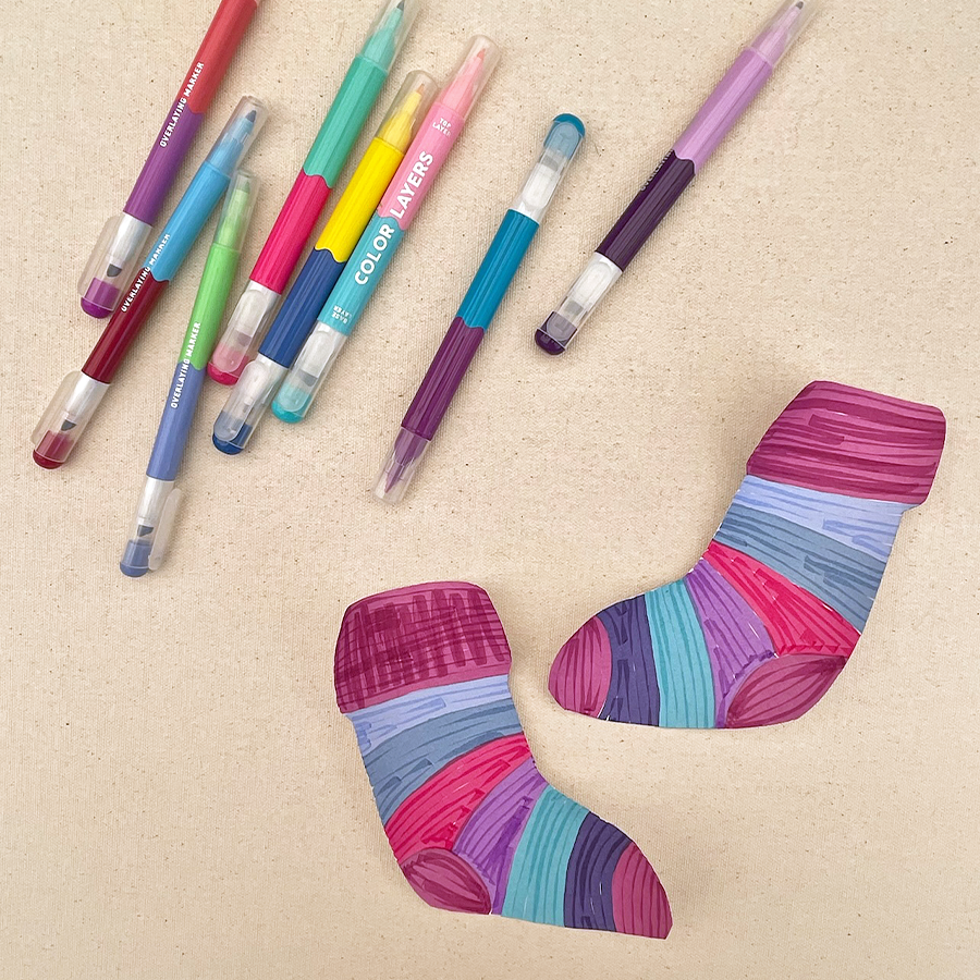 ooly color layers markers on a table next to colorful holiday socks with purple, blue, pink, and more colors