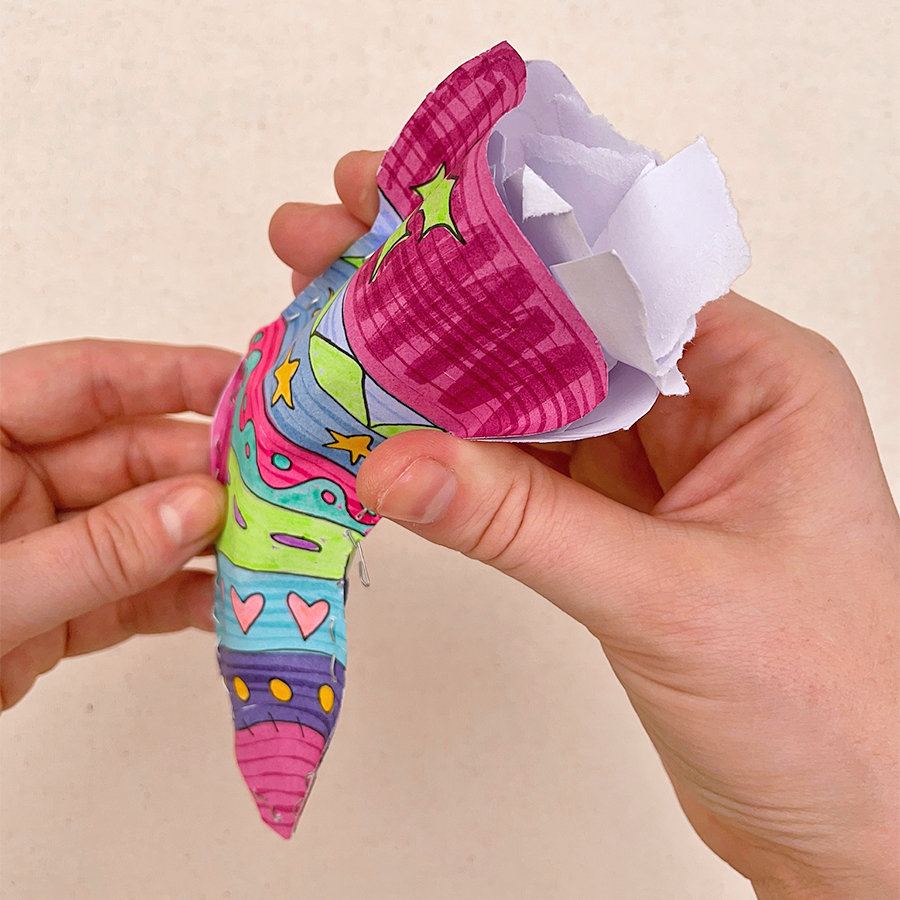 Hand holding stapled, colorful Holiday sock with scrap paper coming out of it