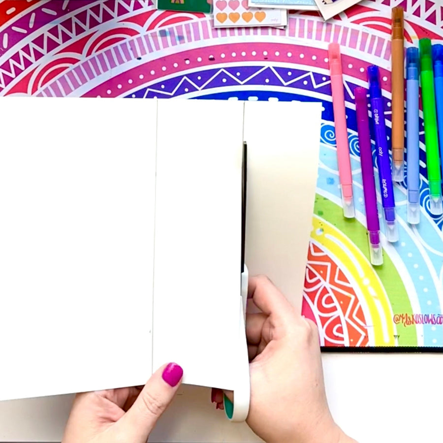 Cutting strips of white paper over colorful background for a craft