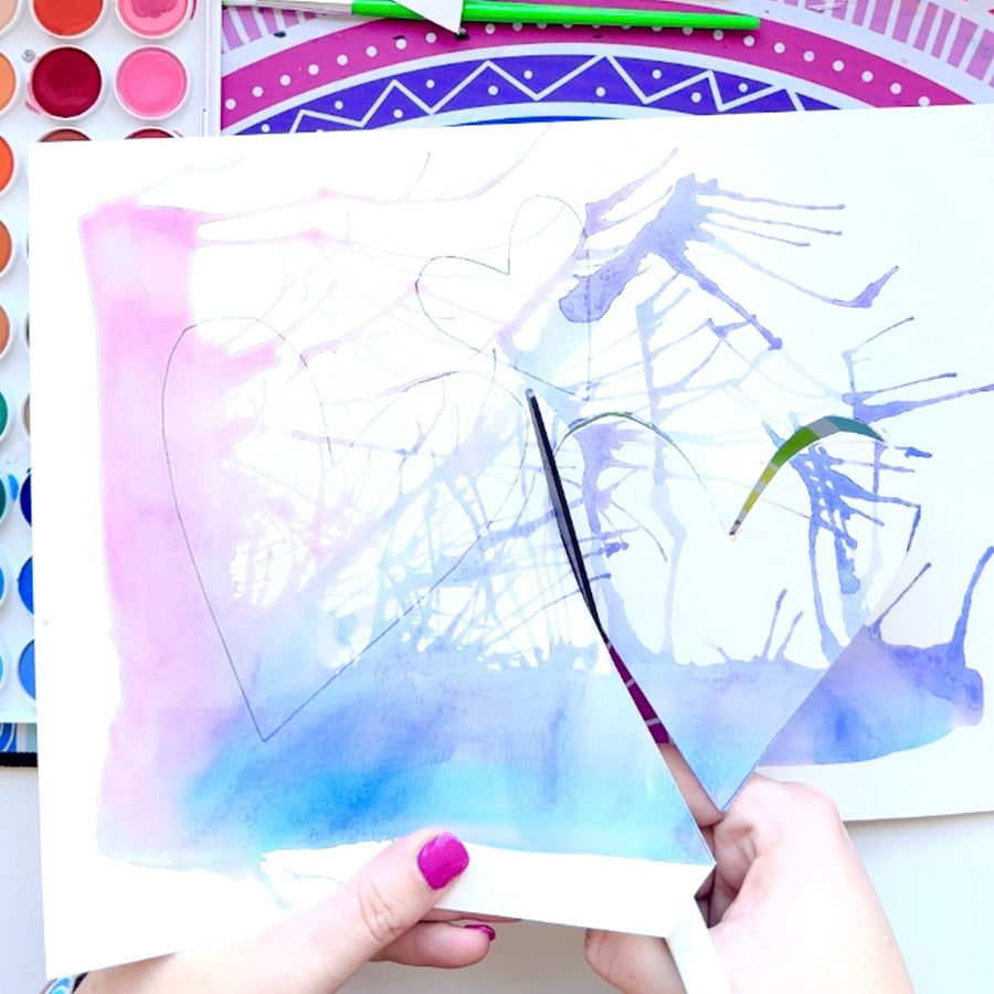 Cutting out heart shape of watercolor abstract painting